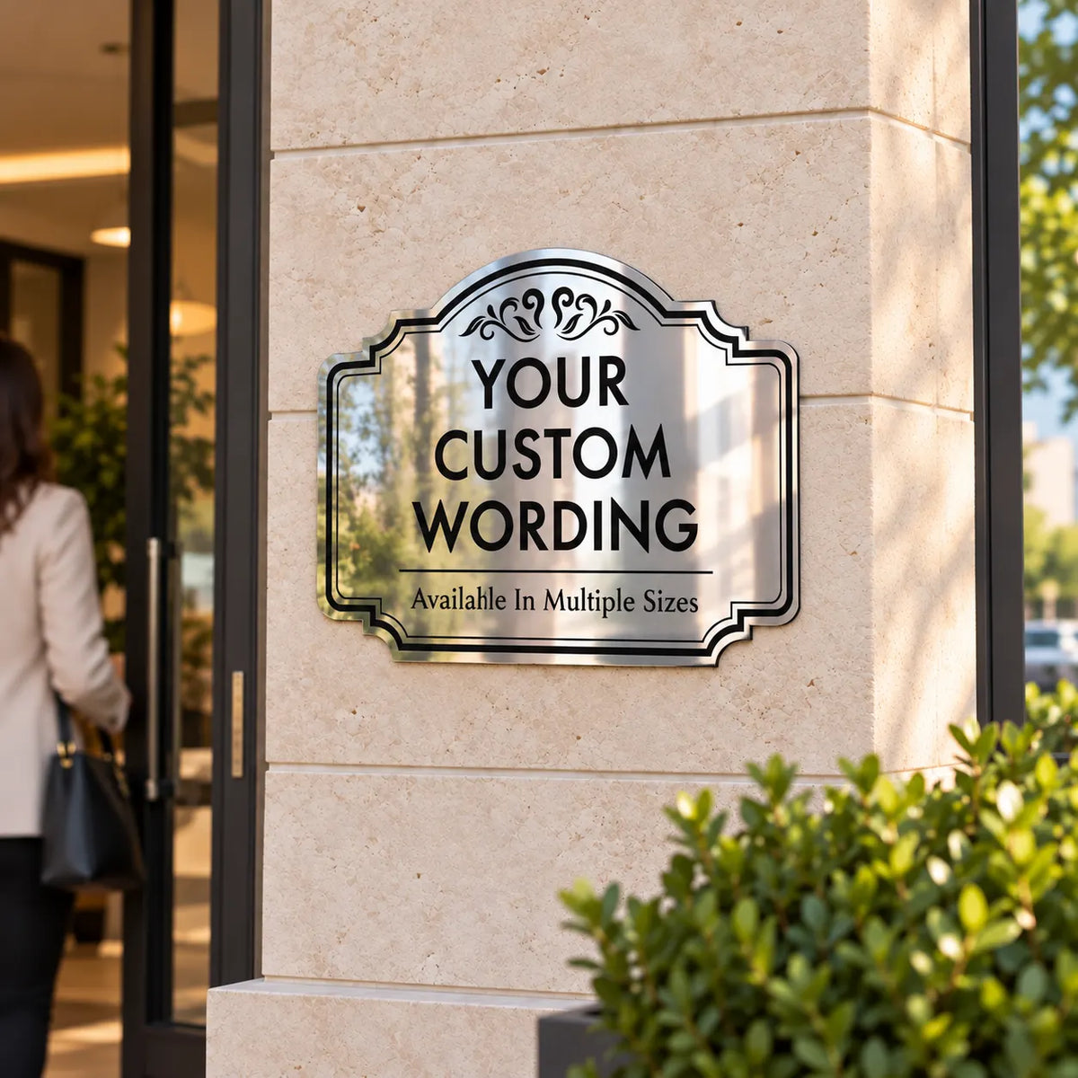 Silver mirror business sign with scalloped scroll border mounted on a stone pillar beside a shop door