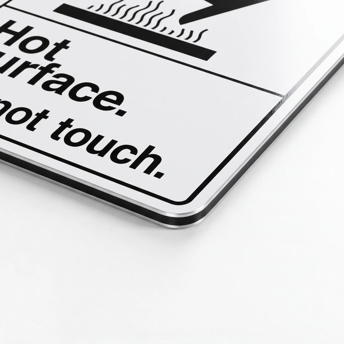 A close-up of a white hot surface warning sign with black text reading 'Hot surface. Do not touch.