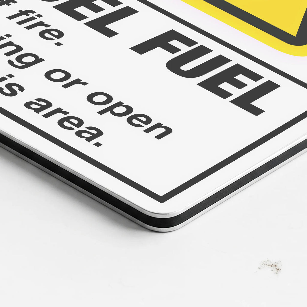A close-up of a white safety sign with black text warning against fire or open areas, featuring bold black lettering and a yellow triangular section at the top right.