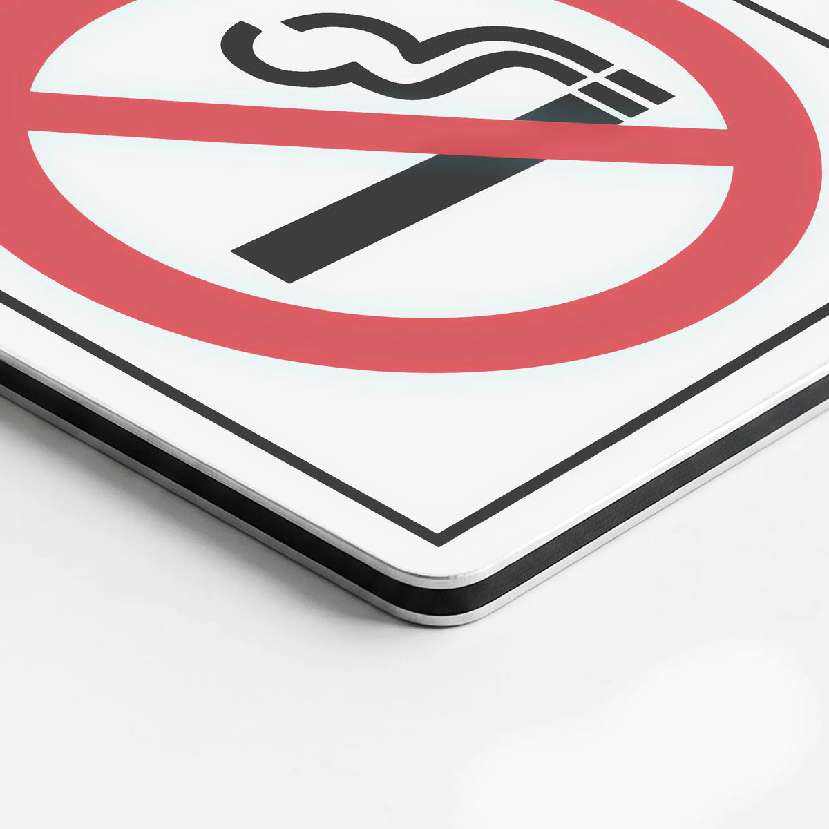 A close-up of a square sign showing a no smoking symbol with a red circle and slash over a black cigarette icon on a white background.