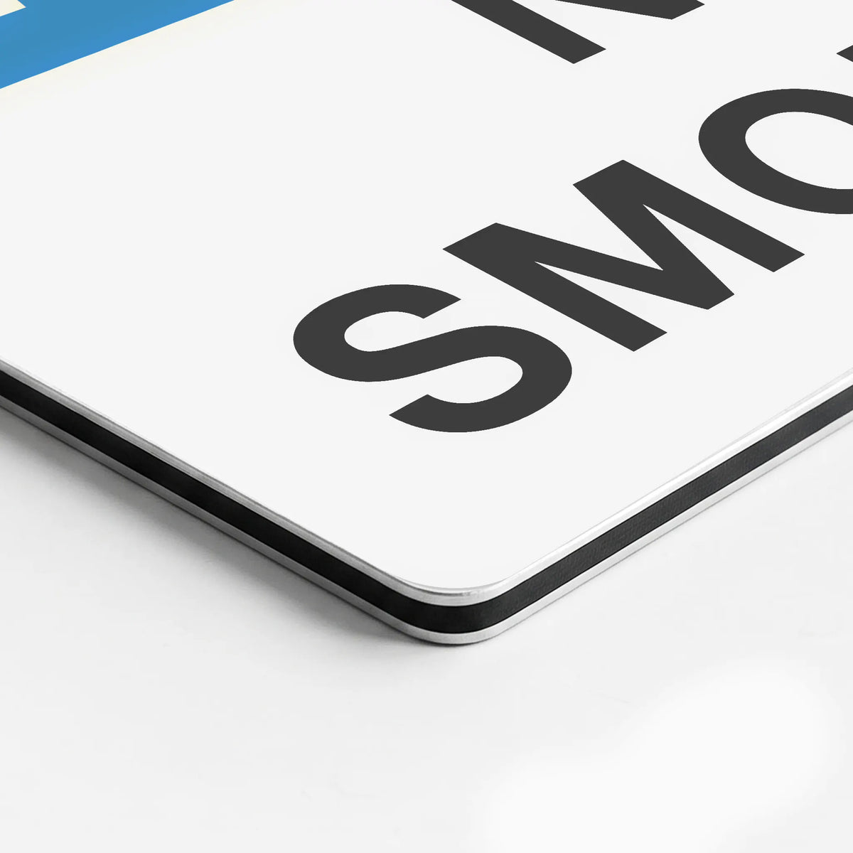 A close-up of a white rectangular sign with bold black text reading 'SMO' and a small blue section in the top-left corner, photographed on a white background.
