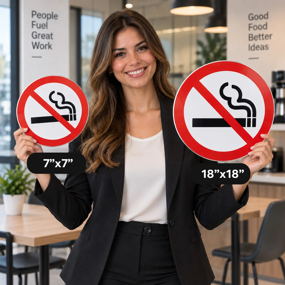 A woman in a black blazer and white top stands in an office holding two round smoking prohibition signs. One sign is labeled 7"x7" and the other 18"x18".