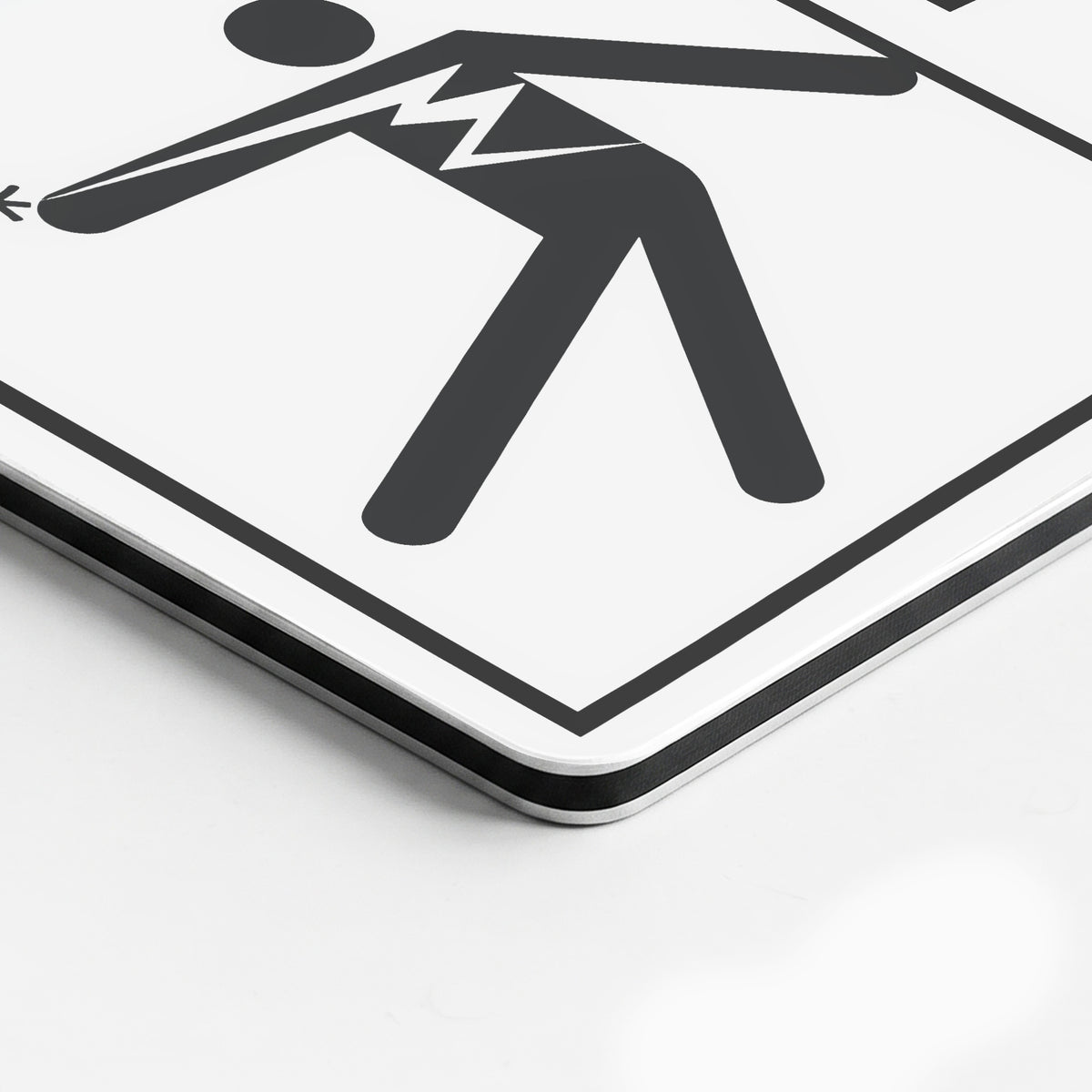 A close-up of a square white sign with a black graphic symbol of a person holding a broken arm, bordered by a thick black frame.